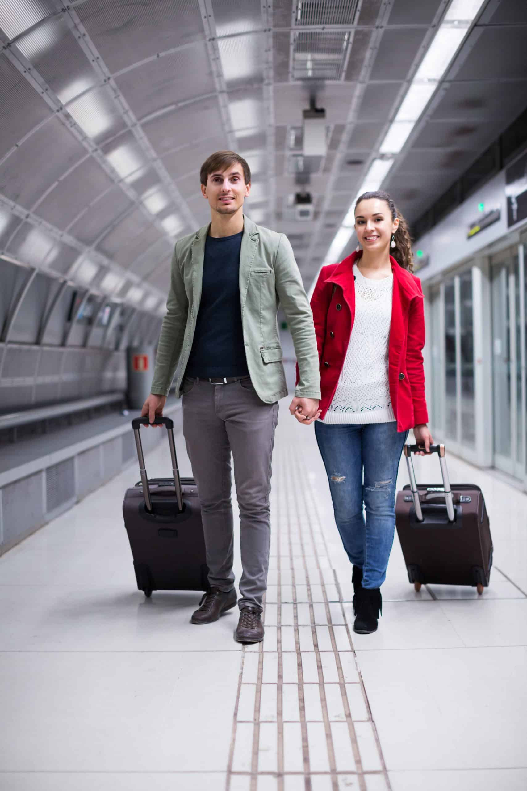 Dos personas en un andén de metro con maletas con ruedas.